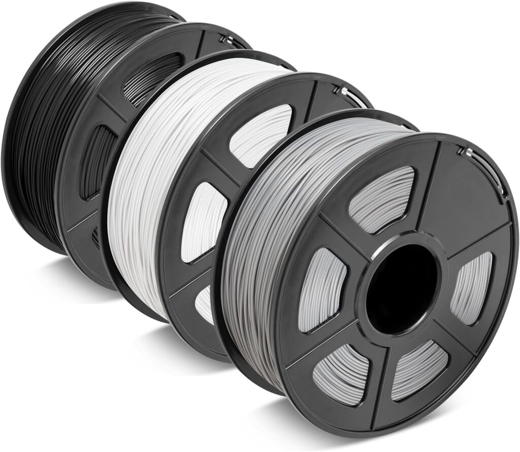 Drei schräg angeordnete Kunststoffspulen mit aufgerolltem 3D‑Druck‑Filament in Schwarz, Weiß und Grau.