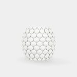 Ovoides weißes Gefäß mit gleichmäßig angeordneten, überlappenden blattförmigen Elementen (Schuppenmuster) vor einfarbig hellem Hintergrund.