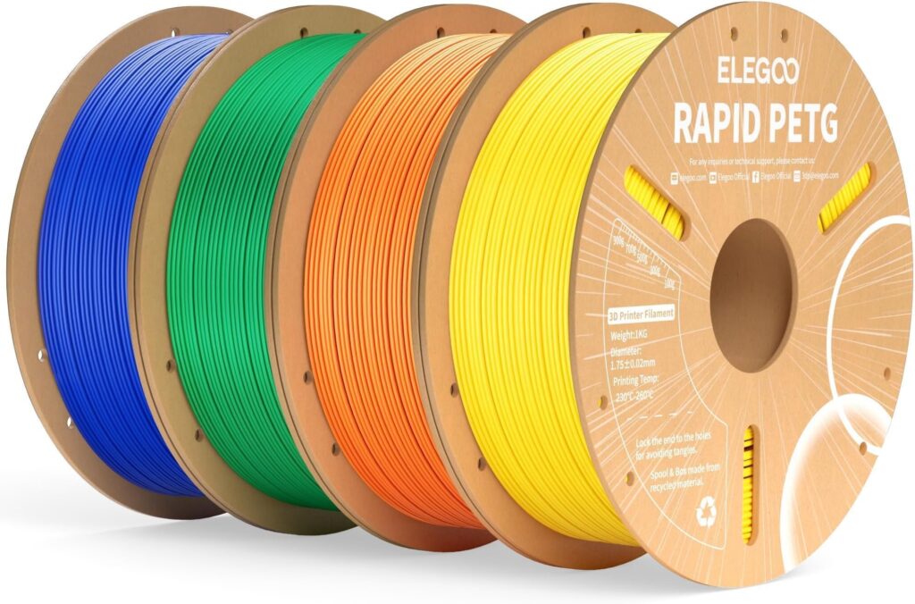 Vier schräg nebeneinander angeordnete Pappspulen mit farbig gewickeltem 3D‑Druck‑Filament (blau, grün, orange, gelb), vorne deutlich sichtbar die beschriftete Spule "ELEGOO RAPID PETG".