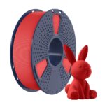 Spule mit rotem 3D-Druckfilament auf dunkelblauer Trommel neben einer kleinen roten 3D-gedruckten Hasenfigur vor weißem Hintergrund.